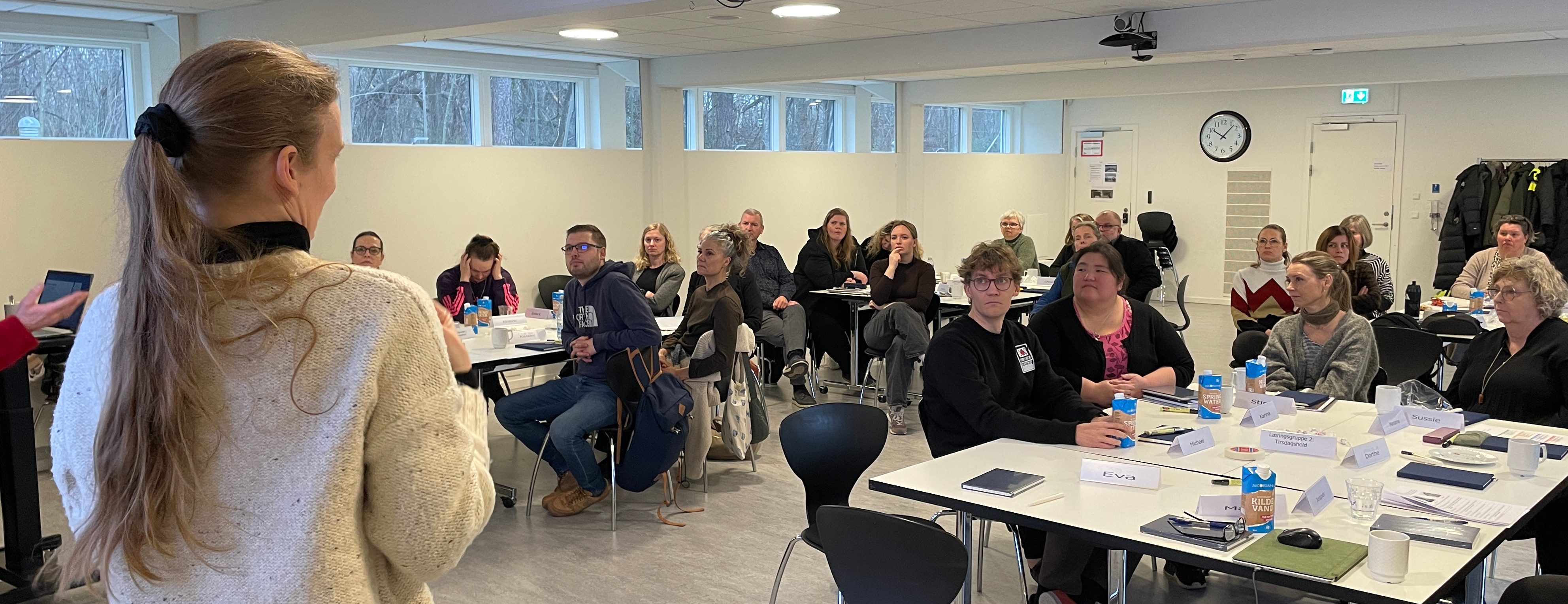 En flok medarbejdere i CFD sidder og kigger hen på kameraet, i front af billedet står en kvindelig tolk med ryggen til.